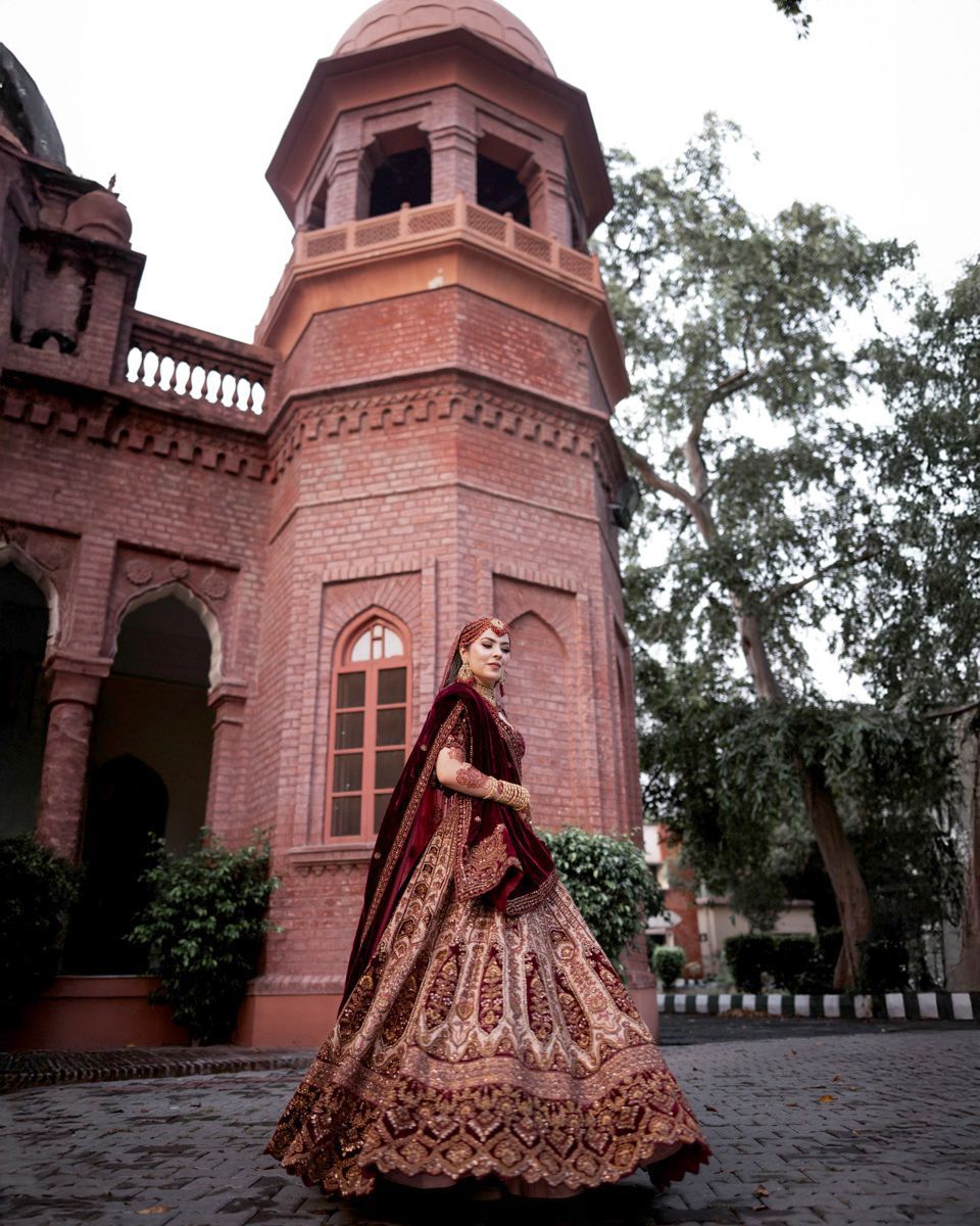 Solo bridal portrait walking before an octagonal domed brick tower, Adam & Sobia's wedding at Chamba House, Lahore