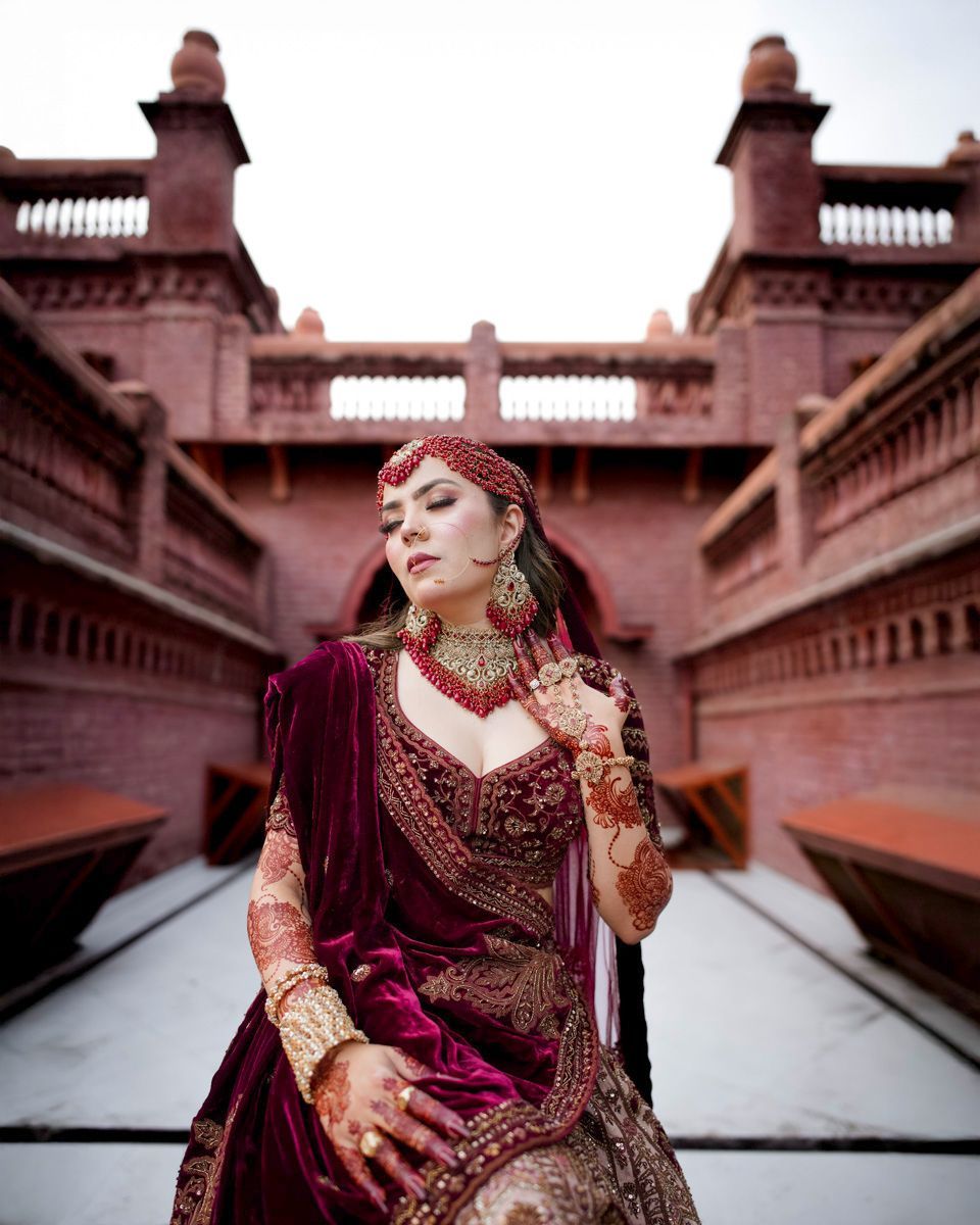 Bride posed between two brick towers connected by a bridge, eyes closed, Adam & Sobia's wedding at Chamba House, Lahore