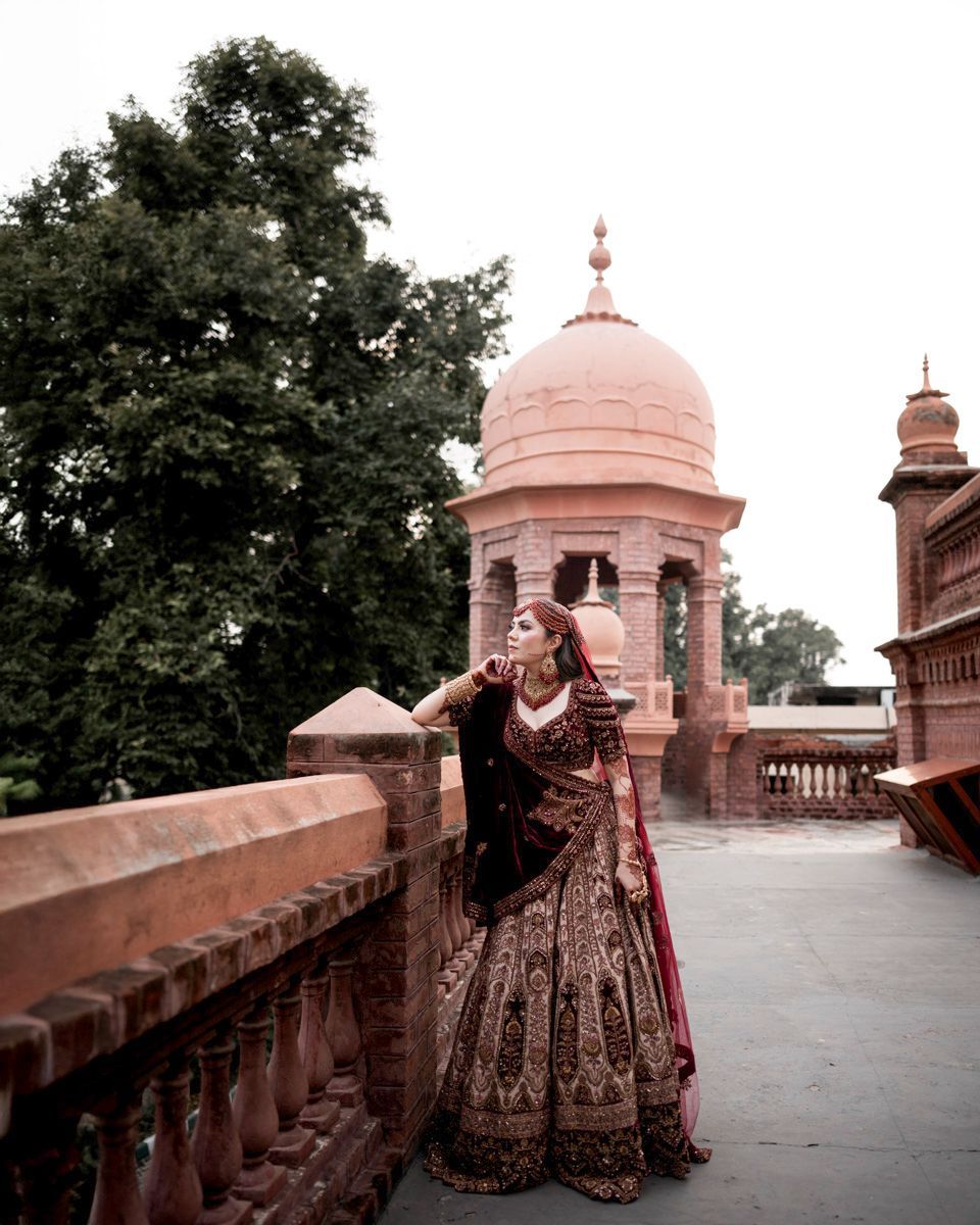 Solo bridal portrait leaning on a brick balustrade with a domed pavilion behind her, Adam & Sobia's wedding at Chamba House, Lahore