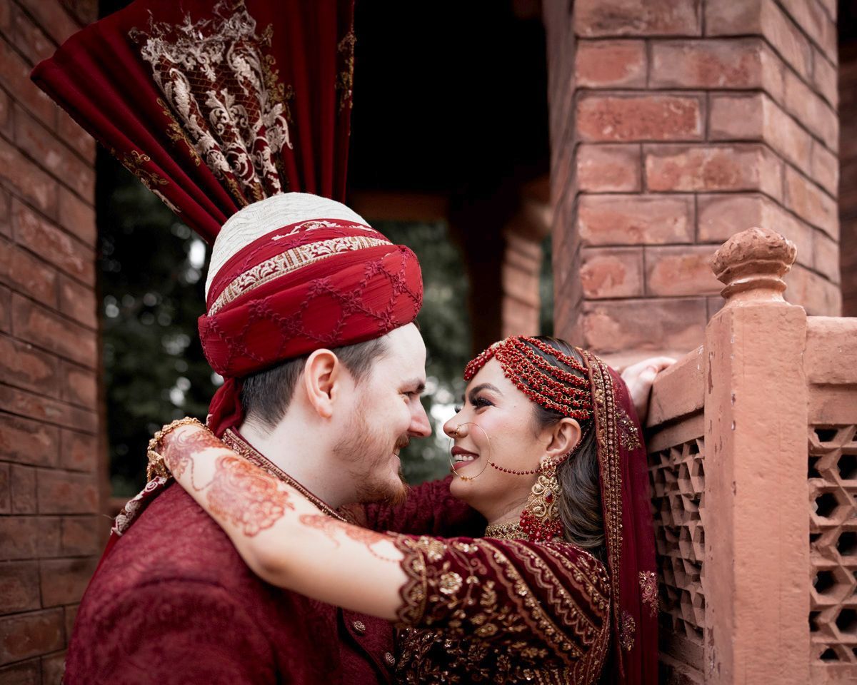 Bride and groom touching noses and smiling beside a brick lattice wall, Adam & Sobia's wedding at Chamba House, Lahore