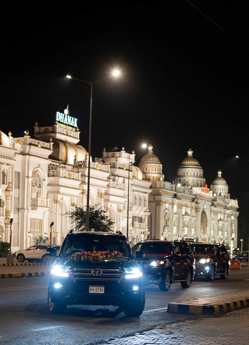 Wedding convoy of flower-decorated SUVs arriving at night outside the Dhanak Events Complex, Adam & Sobia's wedding