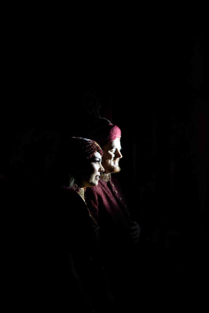 Dramatic side-lit profile portrait of bride and groom against a dark background, Adam & Sobia's wedding