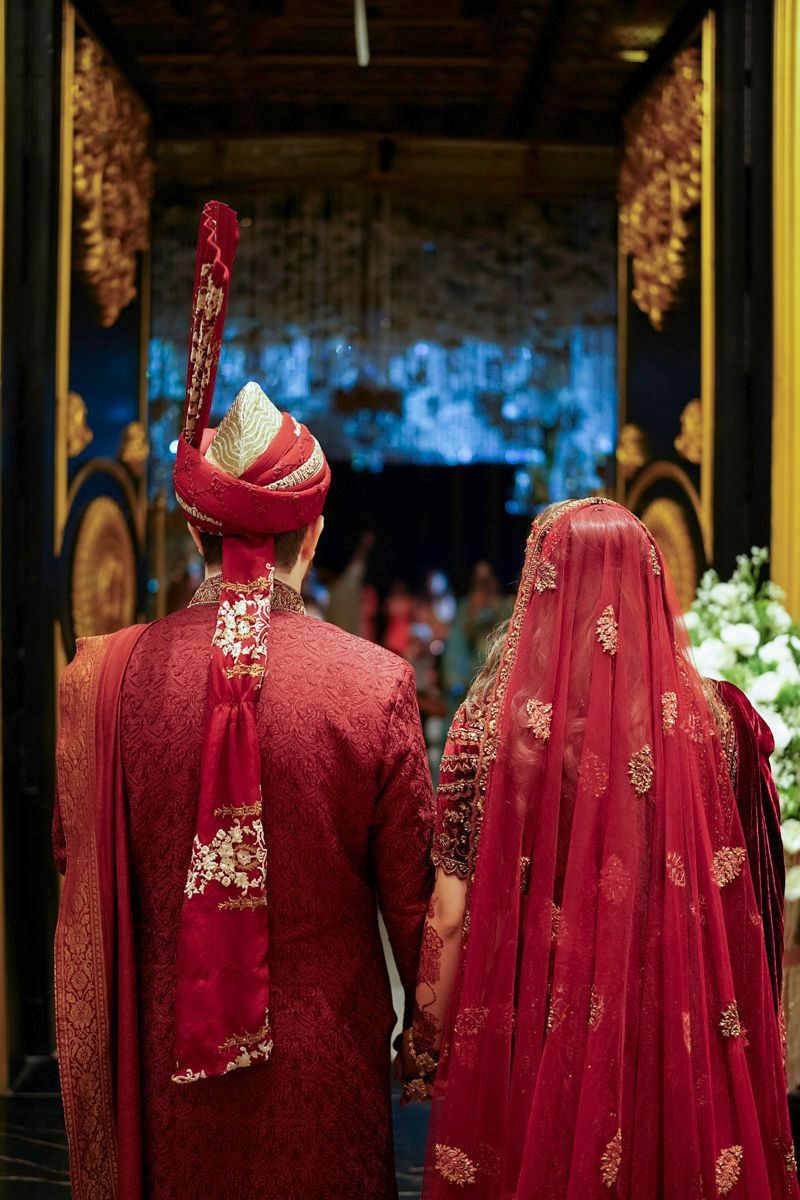Bride and groom viewed from behind walking toward the illuminated reception stage, Adam & Sobia's wedding