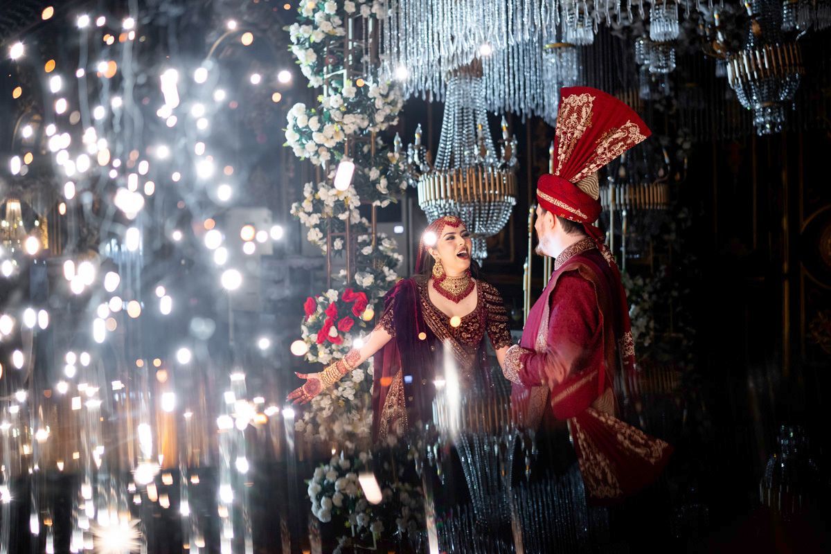 Bride and groom laughing together amid falling sparks and floral decor at the reception, Adam & Sobia's wedding