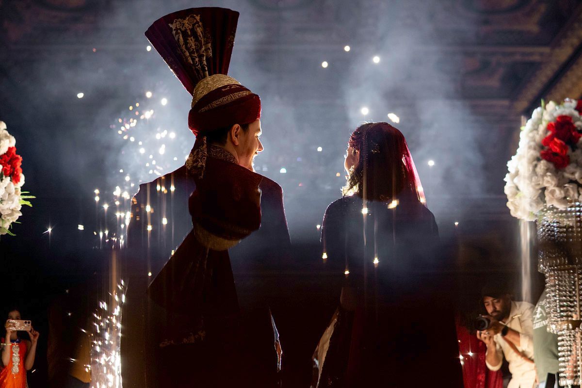 Bride and groom viewed from behind amid drifting cold-spark fireworks and smoke at the reception, Adam & Sobia's wedding