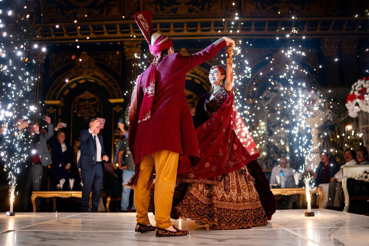 Bride and groom dancing together as cold-spark fireworks shoot up around the dance floor, guests cheering, Adam & Sobia's wedding