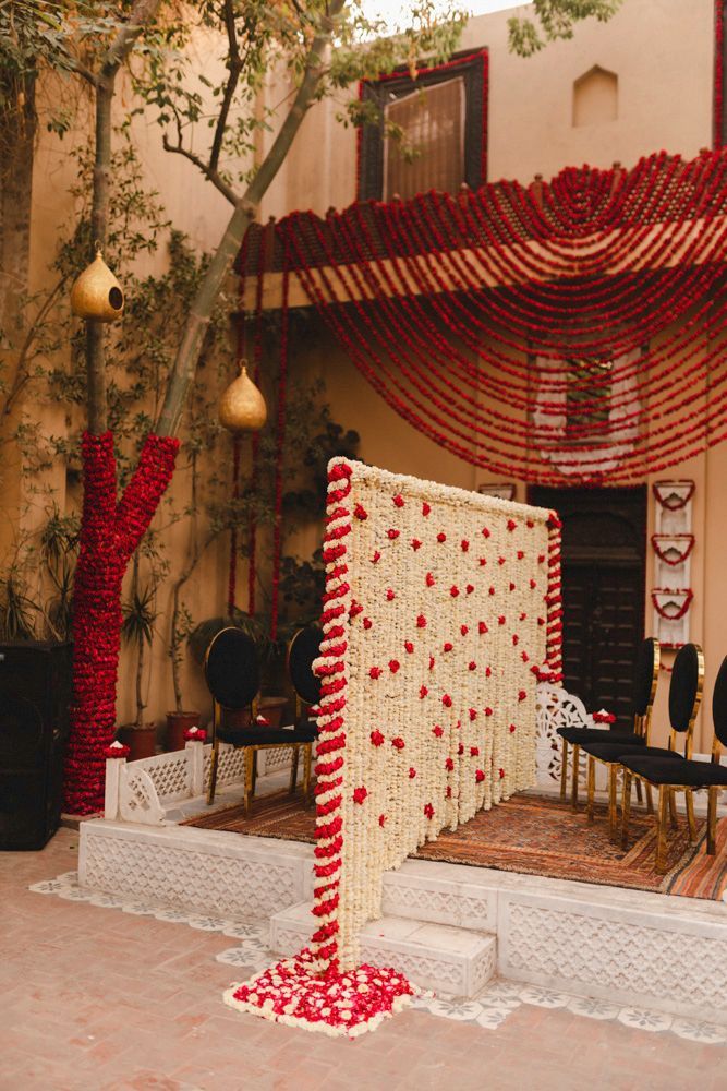 Floral mandap backdrop with red garland draping and a marigold curtain set up for the nikah, Ahmed & Laraib's wedding at Barood Khana Haveli, Lahore