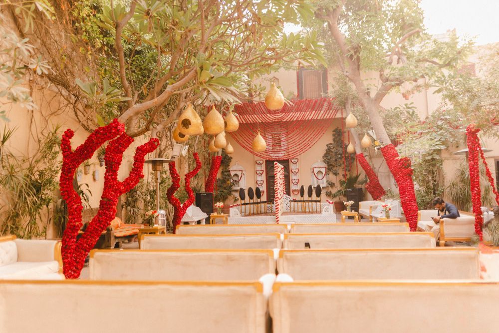 Wide view of the haveli courtyard with red rose-wrapped tree branches and seating for the nikah, Ahmed & Laraib's wedding at Barood Khana Haveli, Lahore