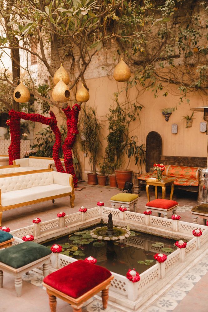 Decor detail of the haveli courtyard with red rose-wrapped branches and a lily pond, Ahmed & Laraib's wedding at Barood Khana Haveli, Lahore