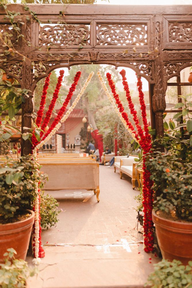 View through a carved wooden archway toward the haveli courtyard's floral nikah setup, Ahmed & Laraib's wedding at Barood Khana Haveli, Lahore