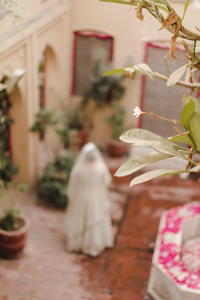 Bride blurred in the background of the haveli courtyard, a frangipani blossom in soft focus in the foreground, Ahmed & Laraib's wedding
