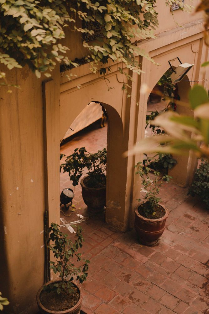 View through a second haveli archway into the courtyard with potted plants, Ahmed & Laraib's wedding at Barood Khana Haveli, Lahore