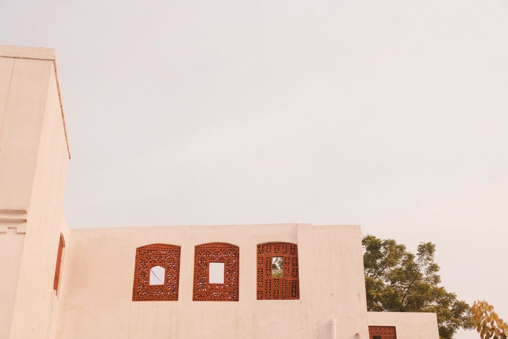 Detail of the haveli's perforated red sandstone window screens against the sky, Ahmed & Laraib's wedding at Barood Khana Haveli, Lahore