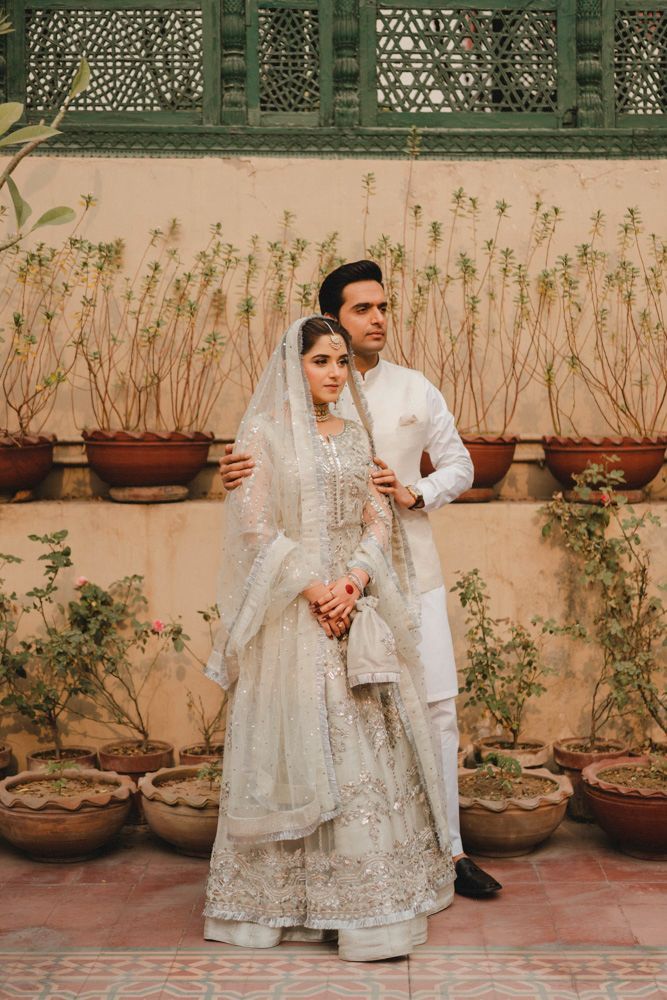 Bride and groom standing together against a wall lined with potted plants at the haveli, Ahmed & Laraib's wedding