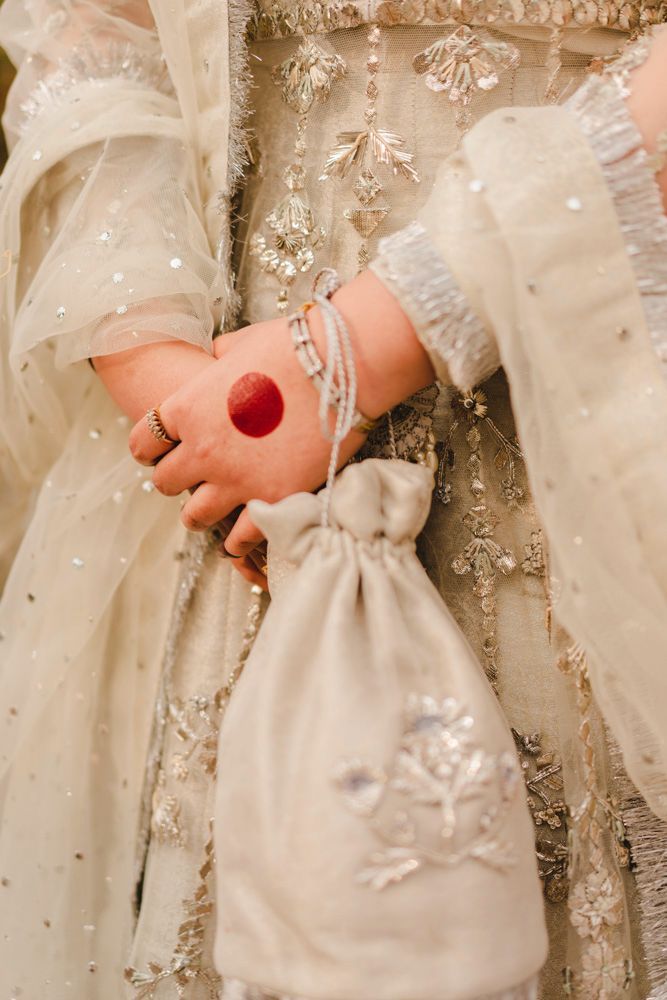 Detail of the bride's hennaed hand resting on her embellished beaded clutch, Ahmed & Laraib's wedding