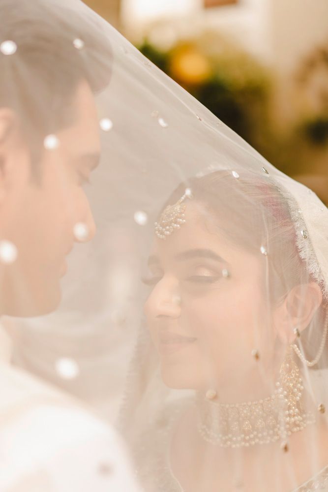 Close-up of bride and groom beneath a sparkling veil draped over both of them, Ahmed & Laraib's wedding
