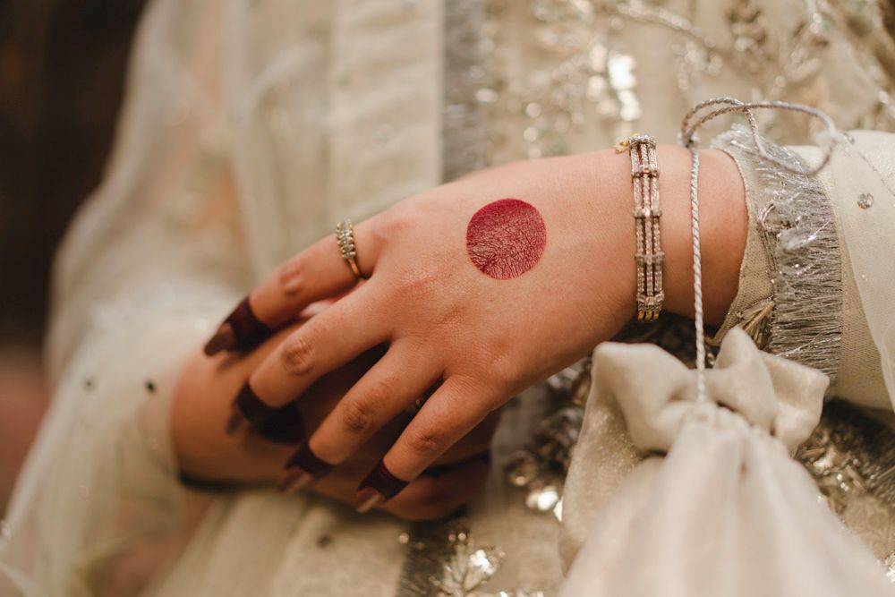 Detail of the bride's hennaed hand with a red dot motif and diamond rings, Ahmed & Laraib's wedding
