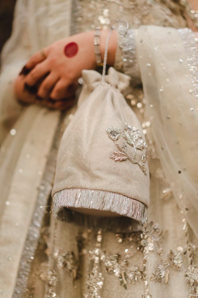Detail of the bride's beaded clutch bag resting against her embellished lehenga, Ahmed & Laraib's wedding