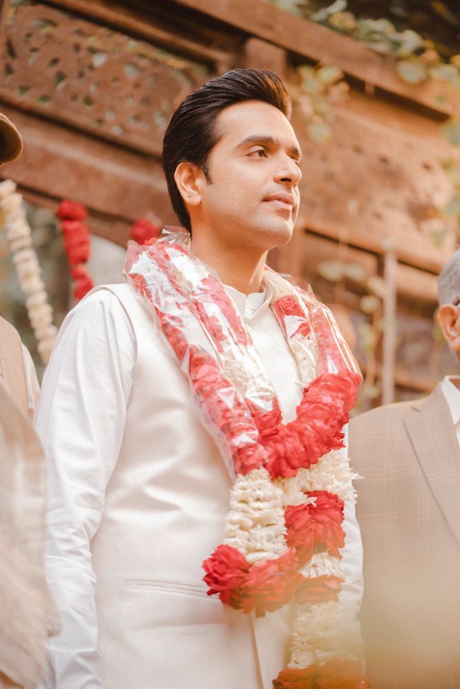 Groom wearing a flower garland looking off to the side during the baraat arrival, Ahmed & Laraib's wedding at Barood Khana Haveli, Lahore