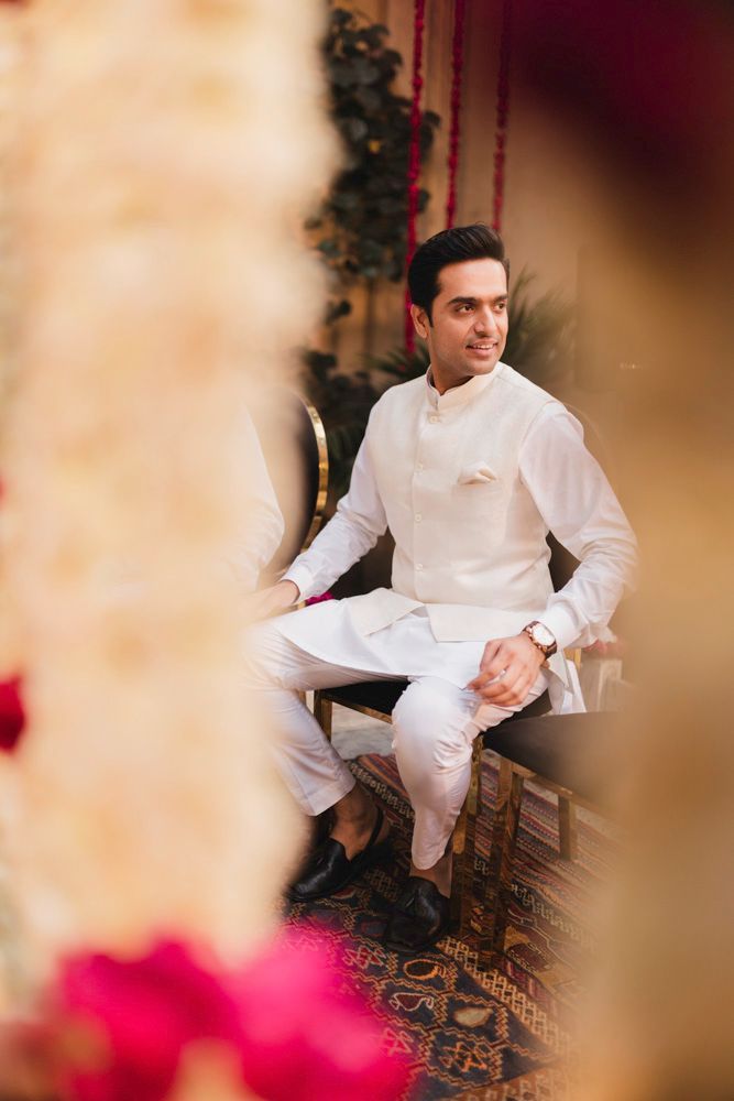 Groom seated for the nikah, viewed through the marigold garland curtain, Ahmed & Laraib's wedding at Barood Khana Haveli, Lahore