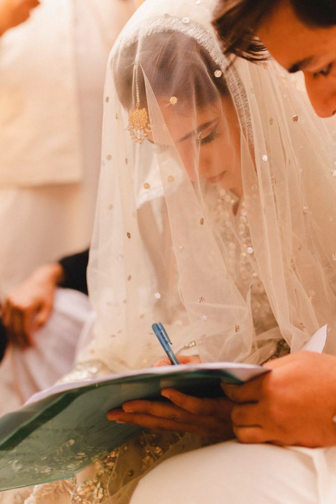 Bride signing the nikah register as the groom looks on, Ahmed & Laraib's wedding