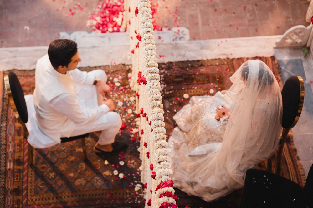 Overhead view of the nikah ceremony, bride and groom seated on either side of the floral pillar, Ahmed & Laraib's wedding at Barood Khana Haveli, Lahore