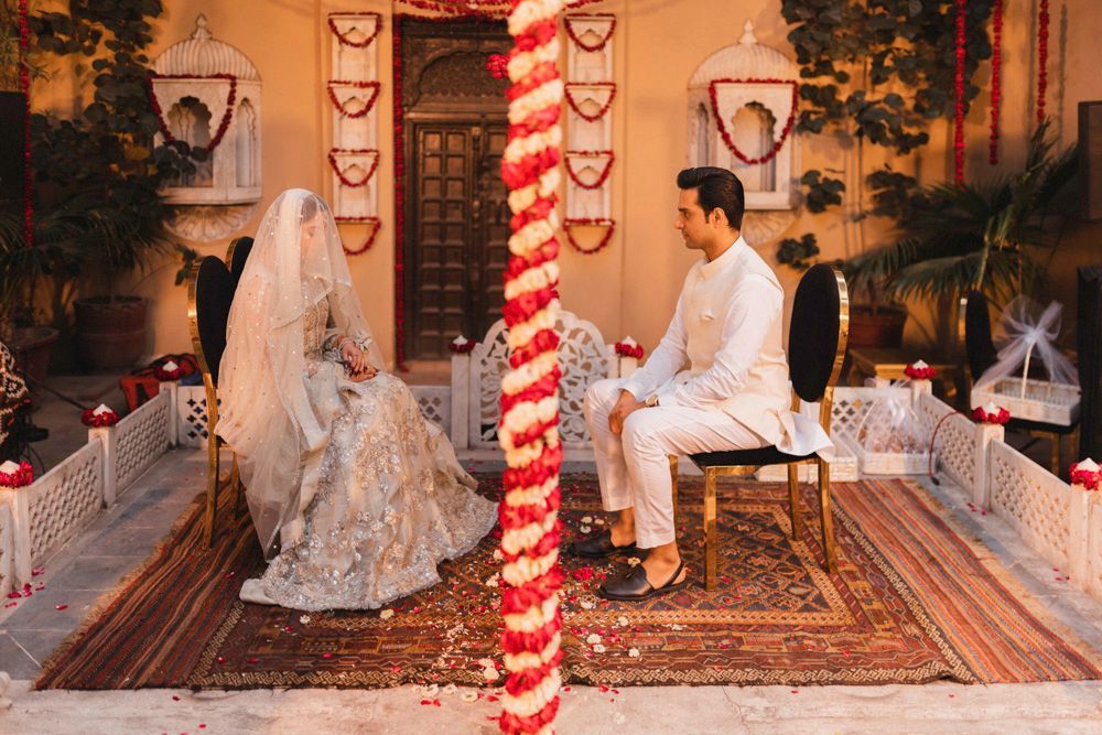 Bride and groom seated for the nikah ceremony with gift baskets visible beside them, Ahmed & Laraib's wedding at Barood Khana Haveli, Lahore