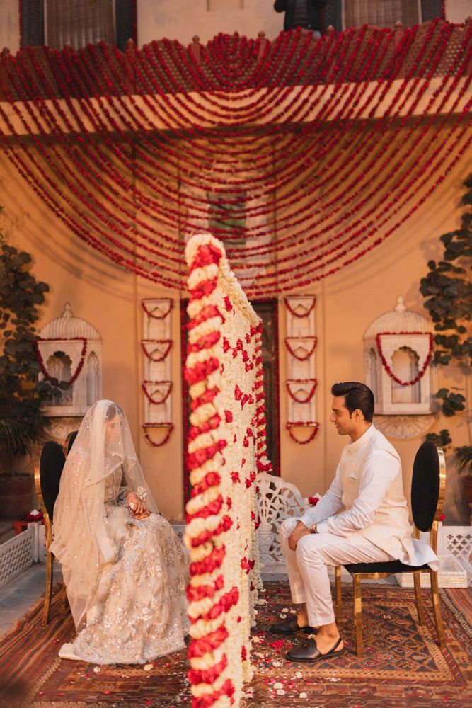 Bride and groom seated for the nikah, a family member visible on the balcony above, Ahmed & Laraib's wedding at Barood Khana Haveli, Lahore
