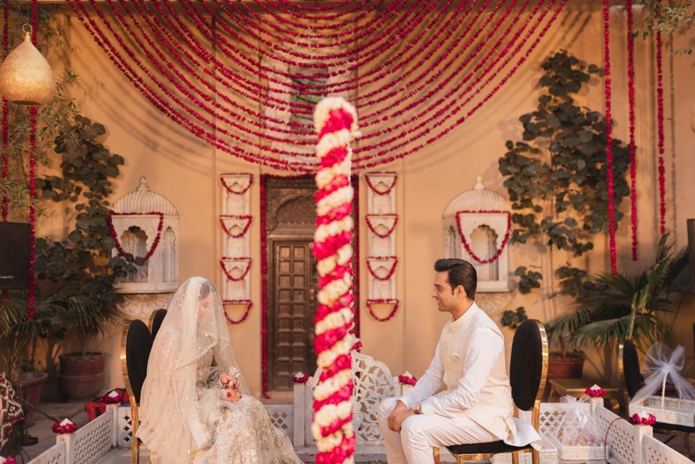 Bride and groom seated for the nikah ceremony, wide symmetrical view of the floral courtyard setup, Ahmed & Laraib's wedding at Barood Khana Haveli, Lahore