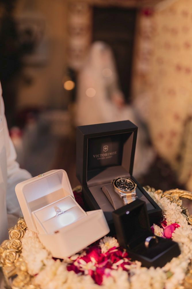 Detail of an engagement ring and wristwatch displayed in gift boxes on a floral tray, Ahmed & Laraib's wedding