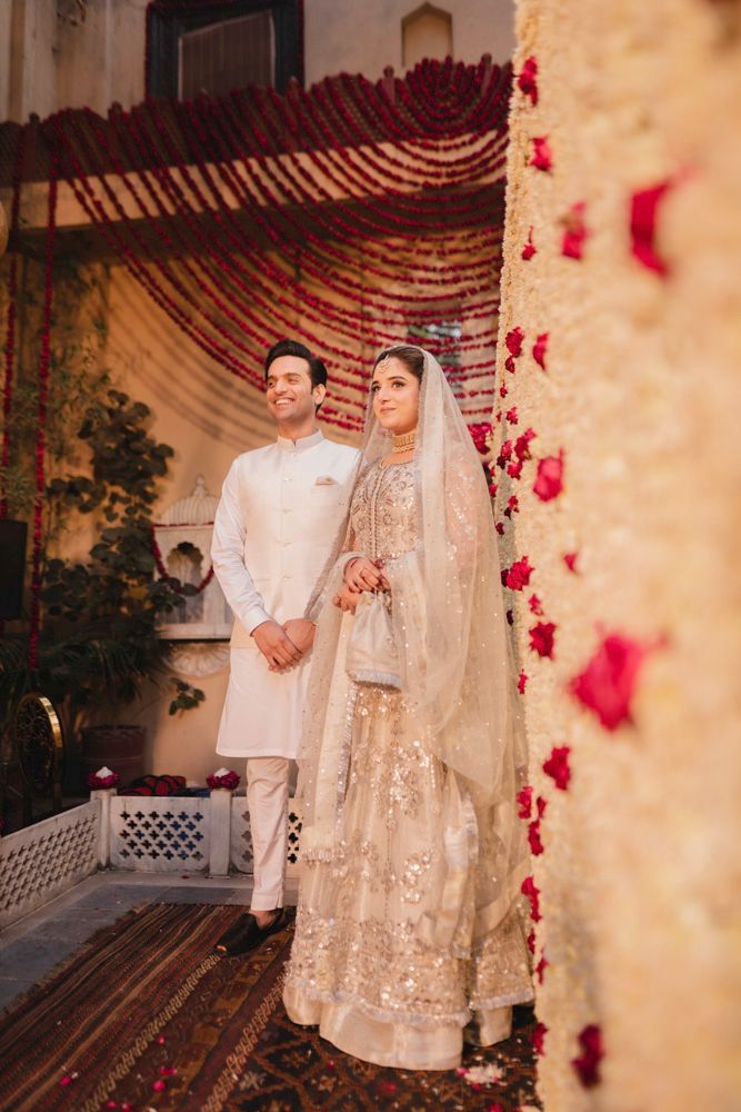 Bride and groom standing close together beside the marigold garland curtain, Ahmed & Laraib's wedding