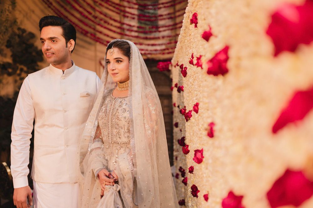 Bride and groom standing close together beside the marigold curtain, both smiling, Ahmed & Laraib's wedding