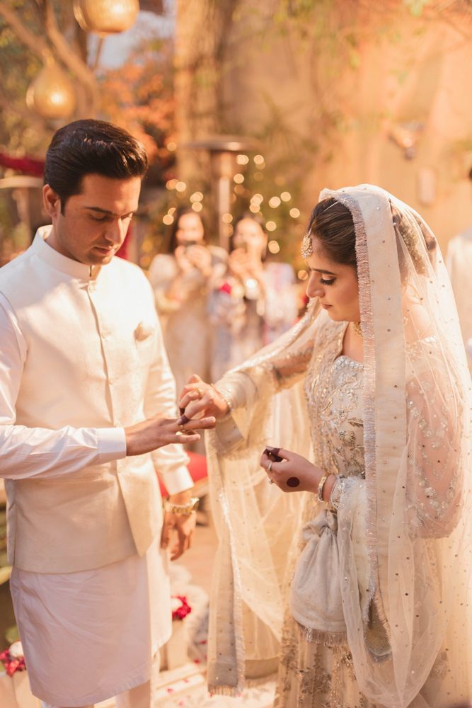 Close-up of the ring exchange between bride and groom, guests visible in the background, Ahmed & Laraib's wedding