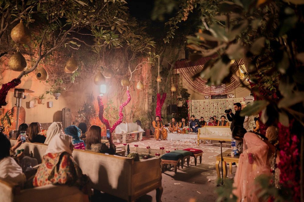 Wide shot of qawwali musicians performing at night for seated guests in the haveli courtyard, Ahmed & Laraib's wedding