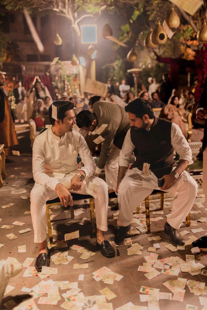 Groom seated with friends amid scattered money notes during the qawwali performance, Ahmed & Laraib's wedding