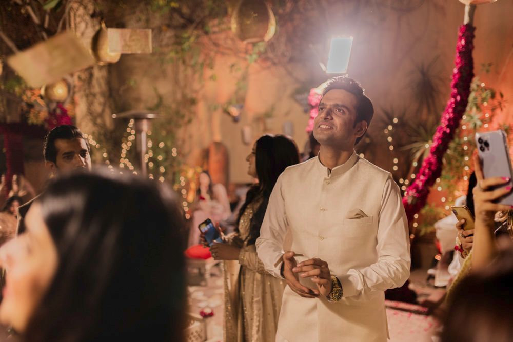 Groom standing among guests at night as money notes float down around him, Ahmed & Laraib's wedding