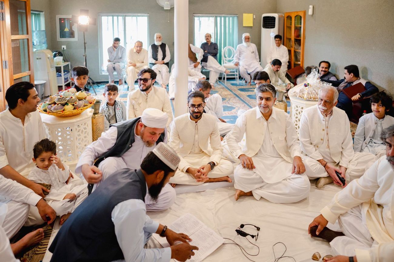 Groom seated cross-legged among male family members for the nikah ceremony, an imam reading from a register, Maham & Aurangzeb's wedding