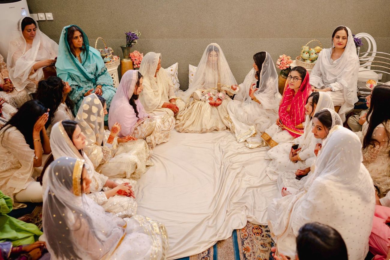 Bride seated among female family members under a sheer veil during the nikah, Maham & Aurangzeb's wedding