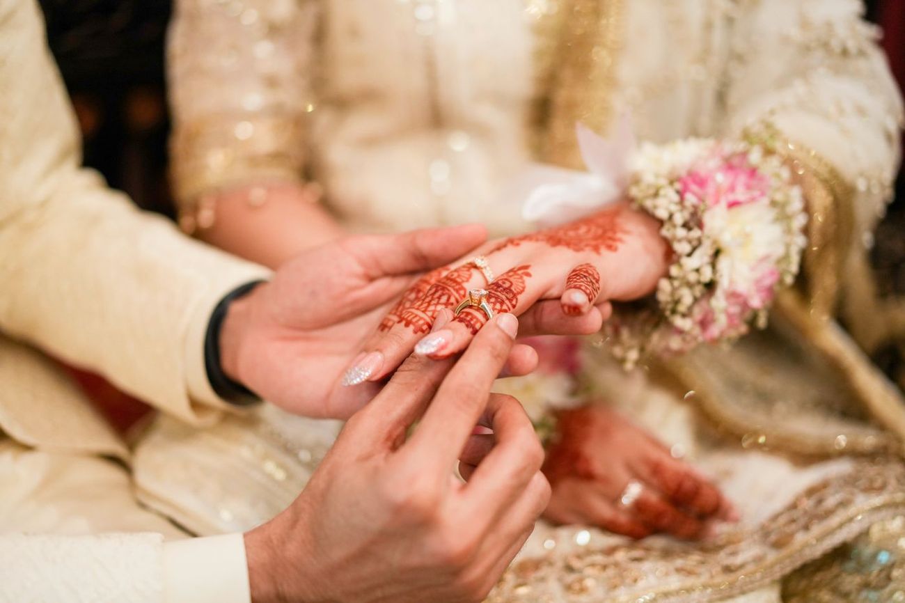 Close-up of the ring exchange between bride and groom, her henna-painted hand visible, Maham & Aurangzeb's wedding