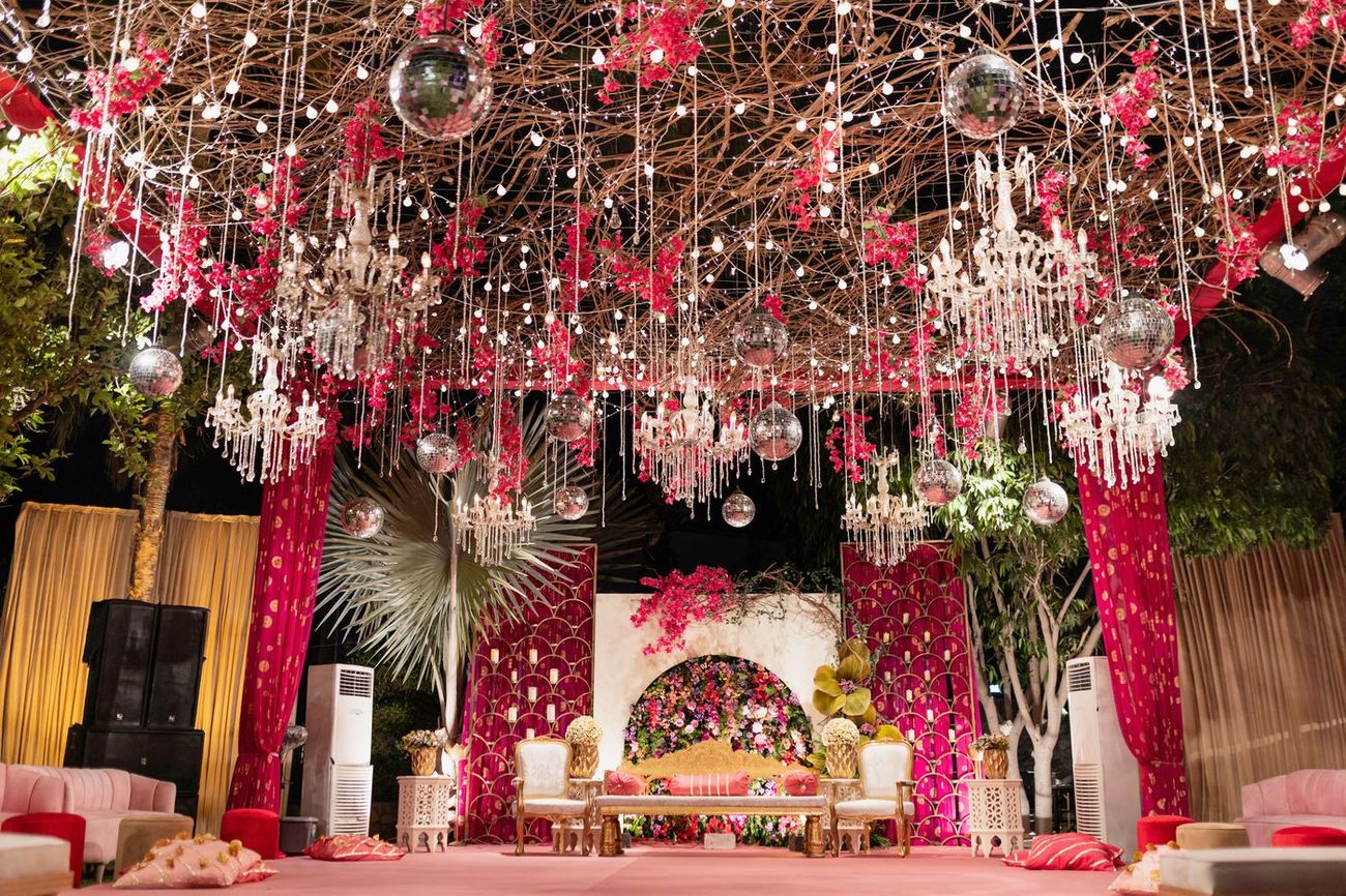 Wide shot of the empty mehndi stage decorated with disco balls, crystal chandeliers, and pink drapery, Maham & Aurangzeb's wedding