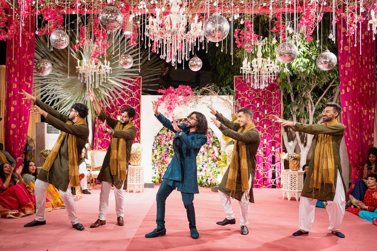 Groom dancing center-stage with friends at the mehndi celebration, arms raised, Maham & Aurangzeb's wedding