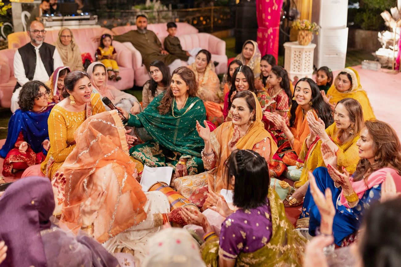 Women singing traditional songs with a dholak drum at the mehndi celebration, Maham & Aurangzeb's wedding
