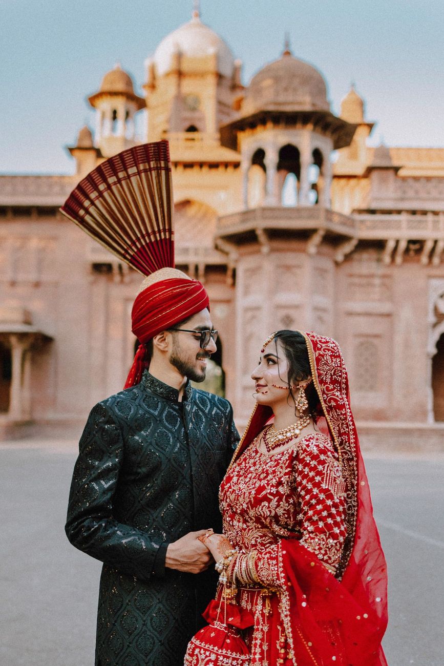 Bride and groom smiling at each other in front of Aitchison College's domed architecture, Maham & Aurangzeb's wedding, Lahore
