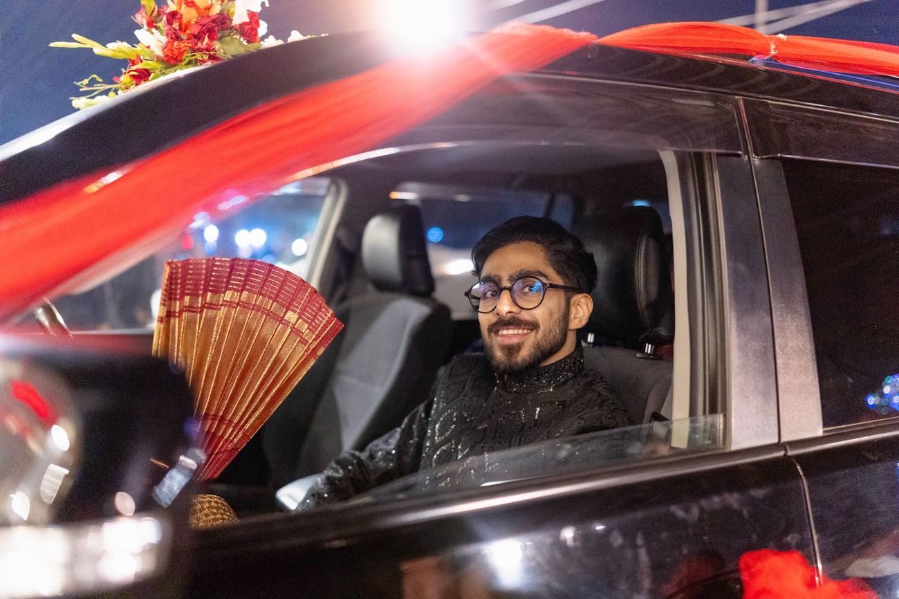 Groom smiling from inside a flower-decorated car during the night-time baraat procession, Maham & Aurangzeb's wedding