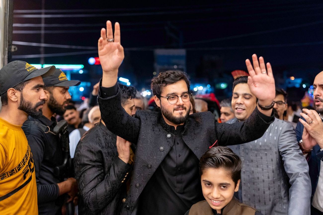 Groom dancing with arms raised among family and friends outdoors at night during the baraat, Maham & Aurangzeb's wedding