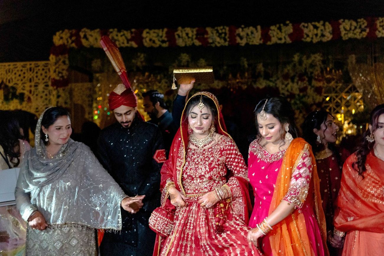Bride's entrance at the reception with a Quran held above her head for blessing, family beside her, Maham & Aurangzeb's wedding