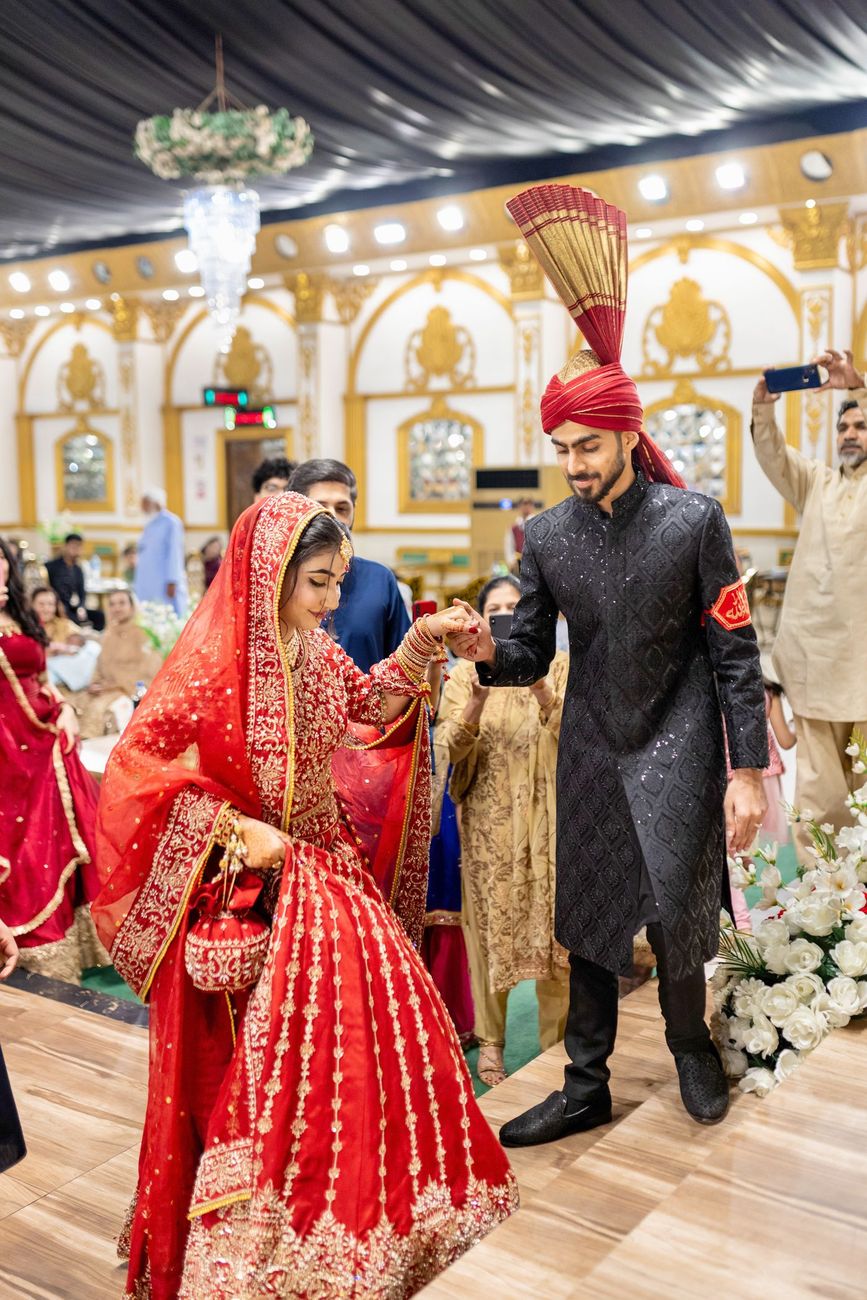 Bride and groom holding hands while walking together at the reception, guests watching, Maham & Aurangzeb's wedding