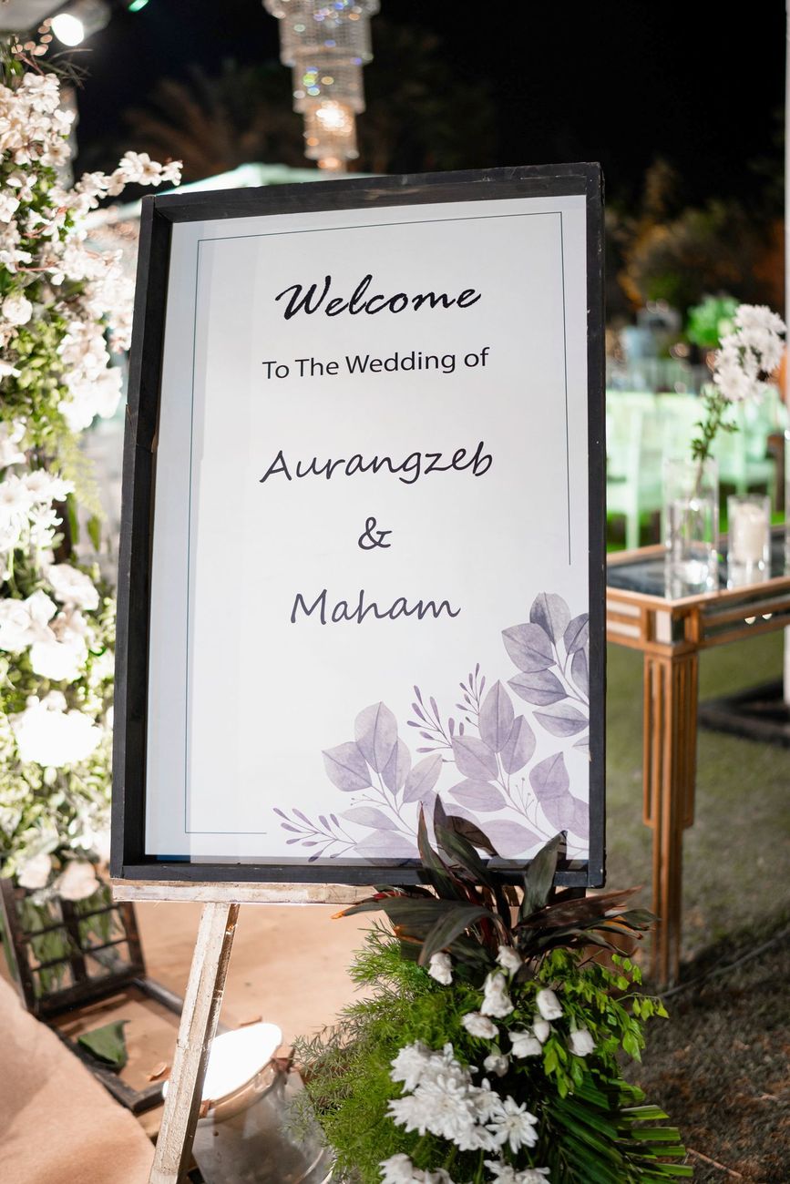 Welcome sign for the wedding of Aurangzeb and Maham, displayed amid white floral decor at the walima venue