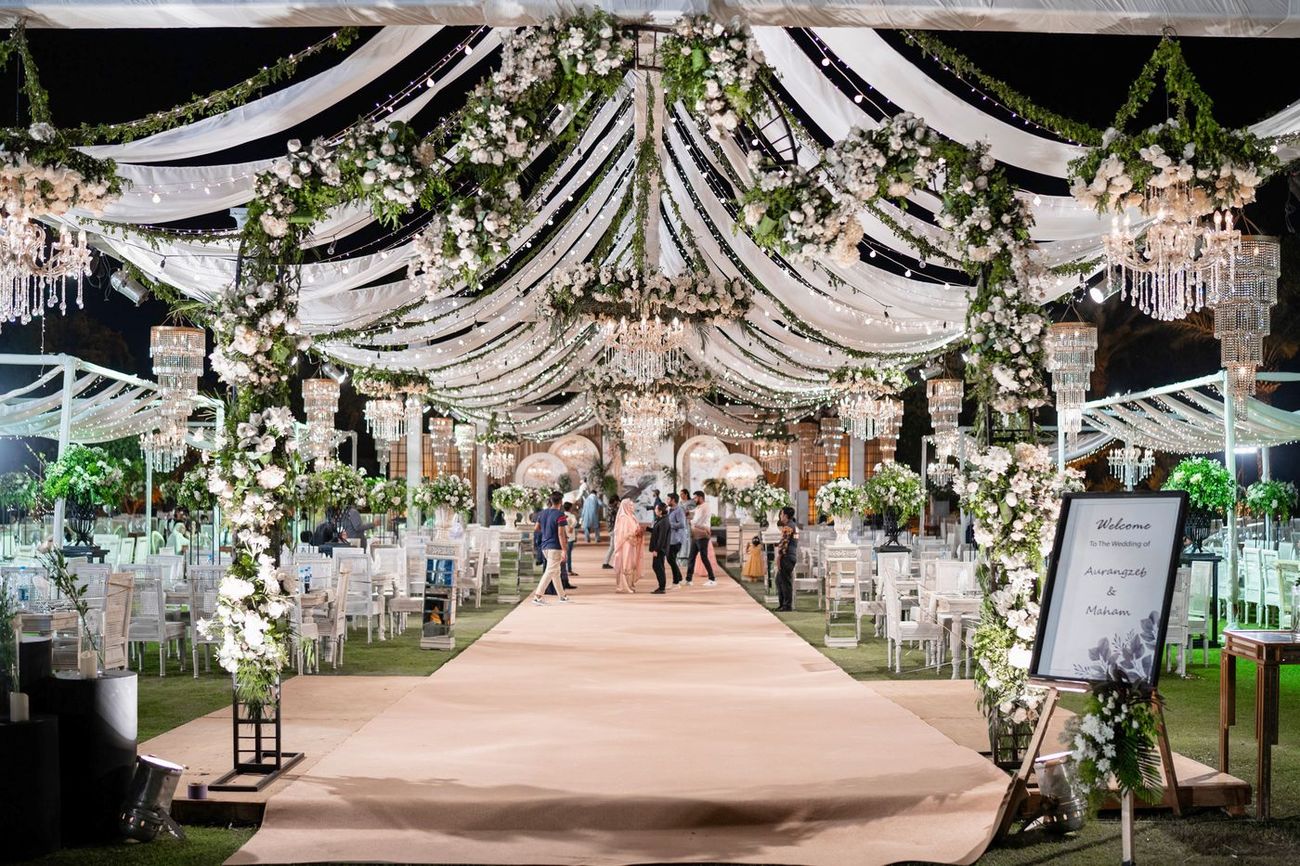 Wide shot of the elegant all-white walima reception venue with draped fabric and floral chandeliers, Maham & Aurangzeb's wedding