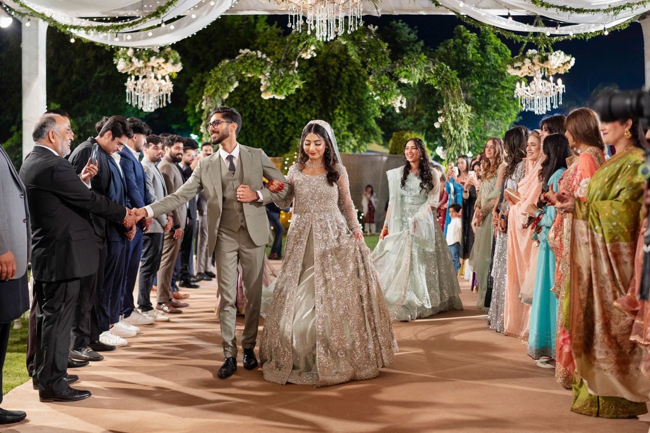 Bride and groom walking down the aisle greeting guests on both sides at the walima entrance, Maham & Aurangzeb's wedding